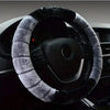 A close-up view of a black steering wheel covered with a thick, gray faux fur plush material.