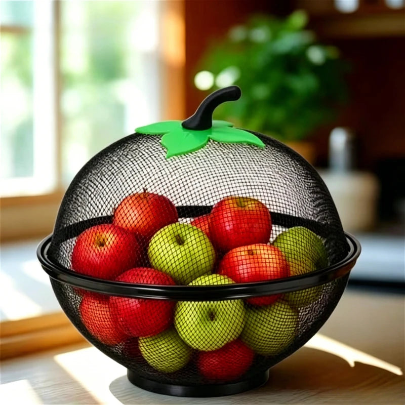 A black metal fruit basket with a green mesh cover filled with red and green apples.