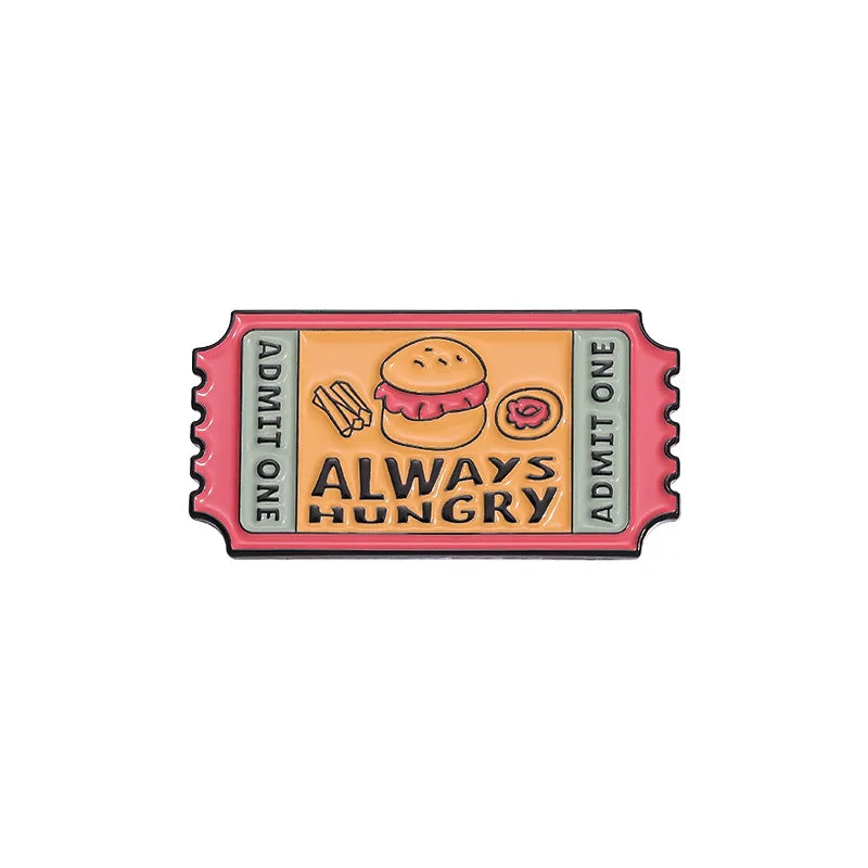 A vintage enamel brooch featuring a hamburger and the text ALWAYS HUNGRY on a pink background.