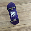 A purple skateboard with a wooden fingerboard and realistic trucks is shown on a light wood surface.