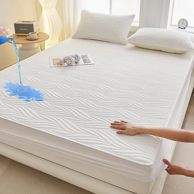 A white fitted mattress protector is shown with a blue liquid dripping onto the surface.