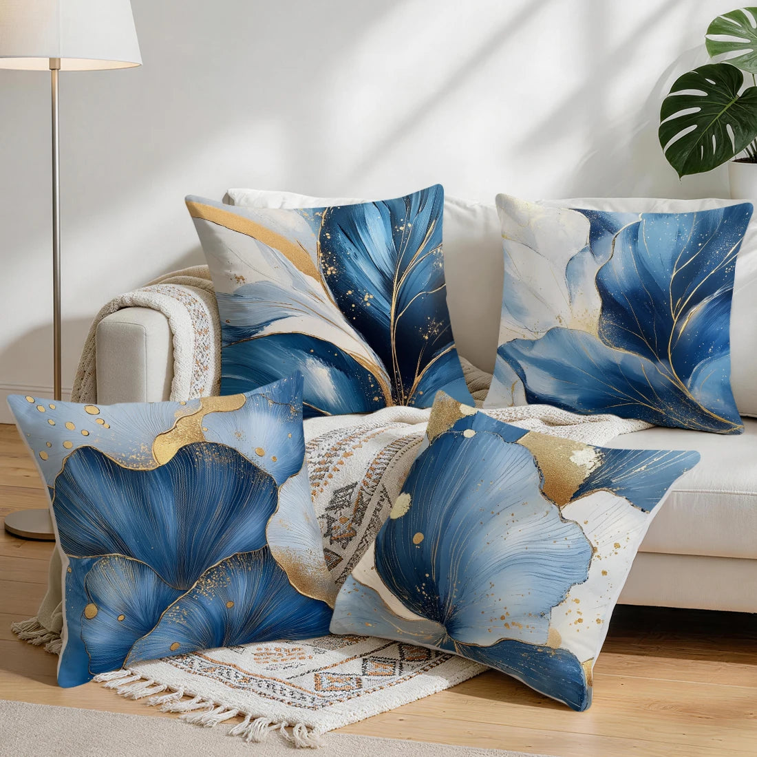 A set of abstract leaf print cushion covers in shades of blue and gold on a white background.