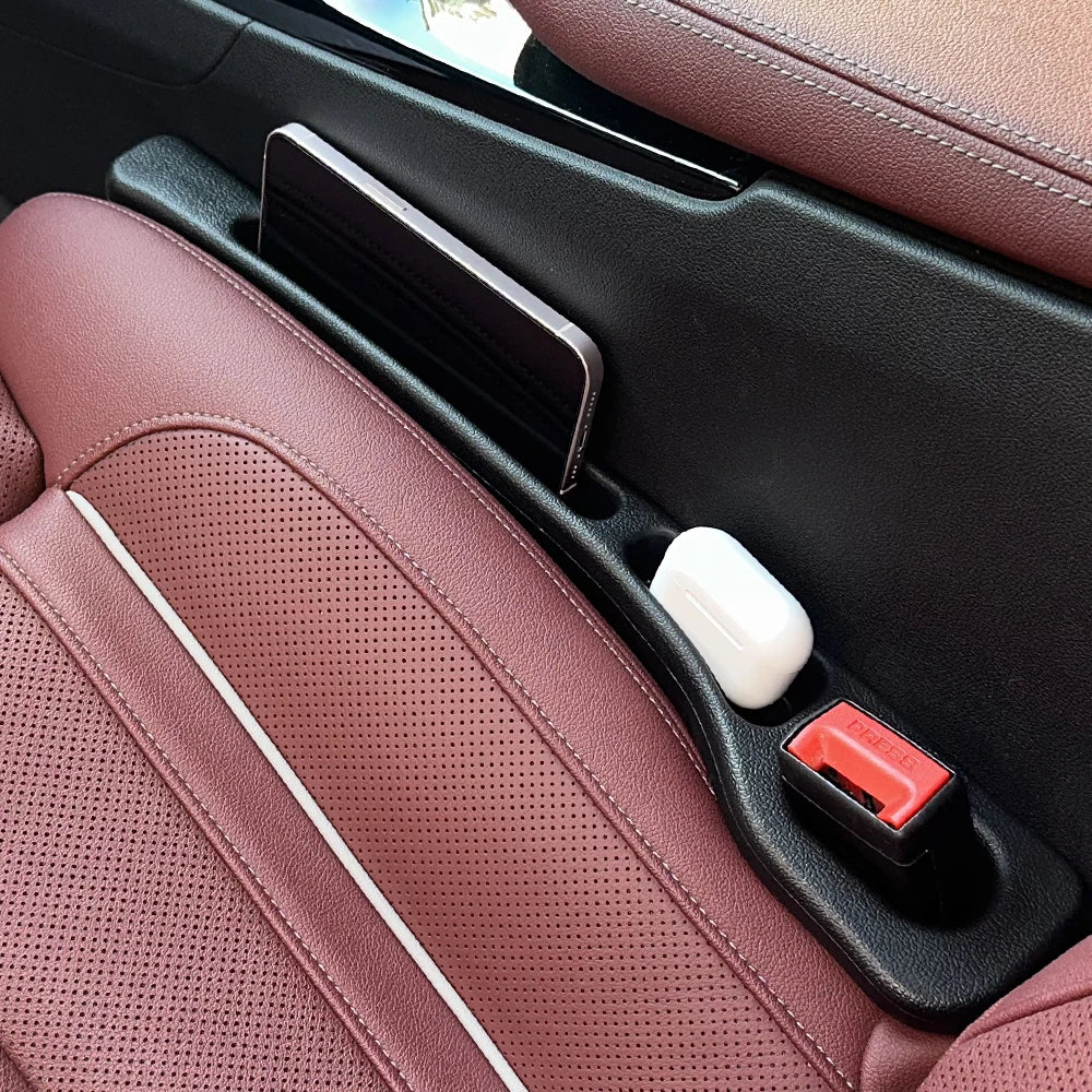 A car seat gap filler and storage organizer with a black and pink leather interior panel.