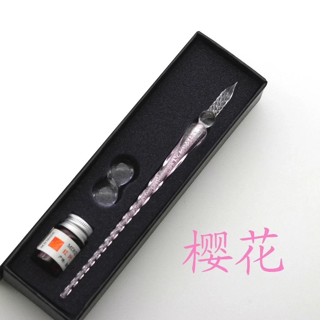 Pluma de inmersión de cristal con tinta dorada, exhibida dentro de una caja negra.