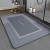 Gray bath mat with a non-slip rubber base placed on a tiled floor.