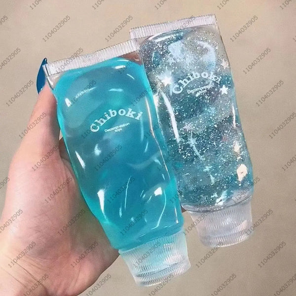 Eine Hand hält zwei klare Stressbälle, einer hellblau und glitzernd.