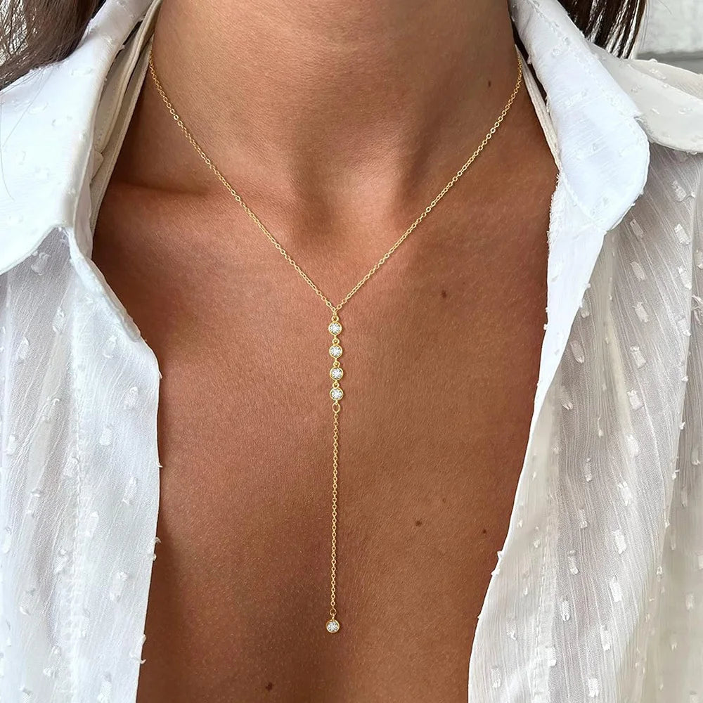 Primer plano de un collar Y de oro con capas y pequeños detalles de diamantes, usado alrededor del cuello.