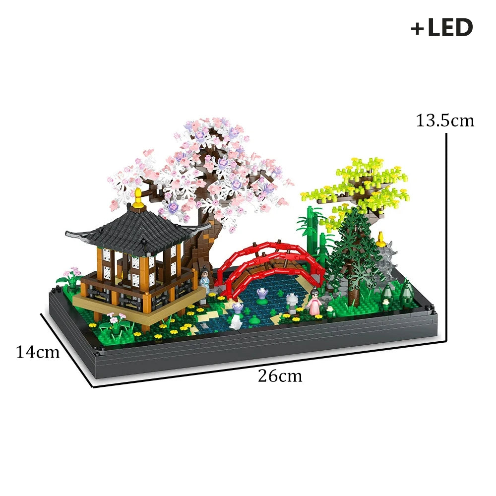 A miniature landscape featuring a traditional Japanese treehouse with pink blossoms, green trees, and a red bridge, illuminat