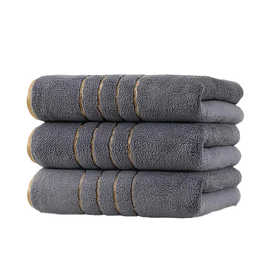 A stack of three gray gold-striped coral fleece towels.