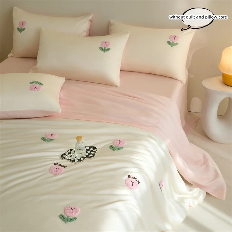 A pink and white embroidered tulip duvet cover set with matching pillowcases on a bed.