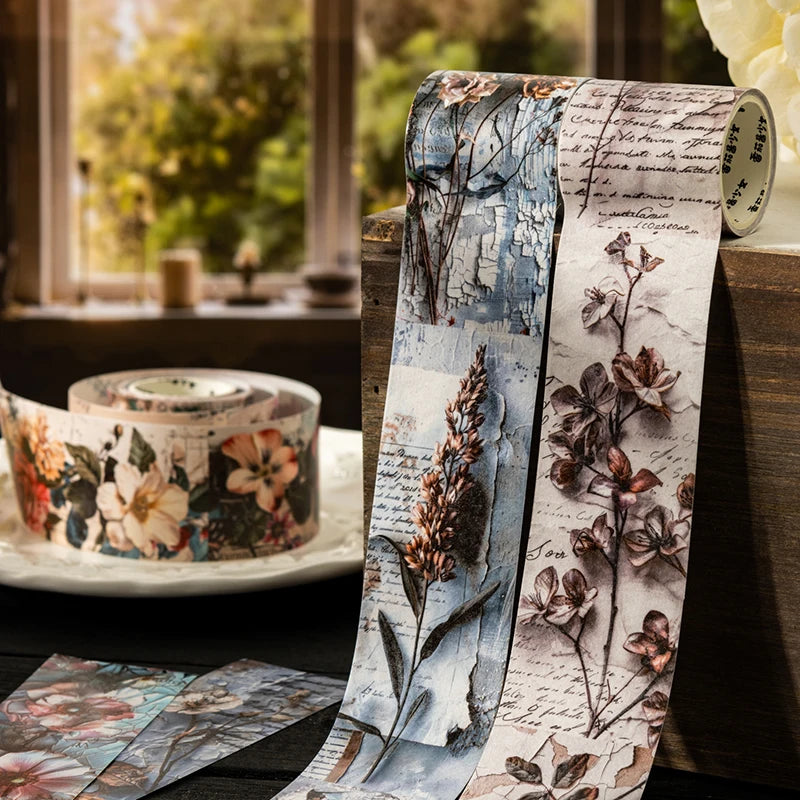 A roll of vintage botanical washi tape featuring pressed flowers and foliage in muted earth tones and soft blues.
