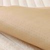 A beige cozy plush anti-slip sofa cushion mat rolled up on a light wooden surface.