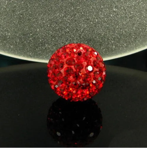 A vibrant red crystal clay round bead resting on a reflective black surface against a gray background.