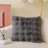 A gray fluffy decorative pillow cover resting on a light-colored sofa.