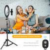 A woman is using a wireless remote control shutter on a selfie ring light setup with a tripod and phone holder.