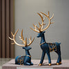 A set of two resin deer figurines in blue and gold, used for Christmas or home decor.