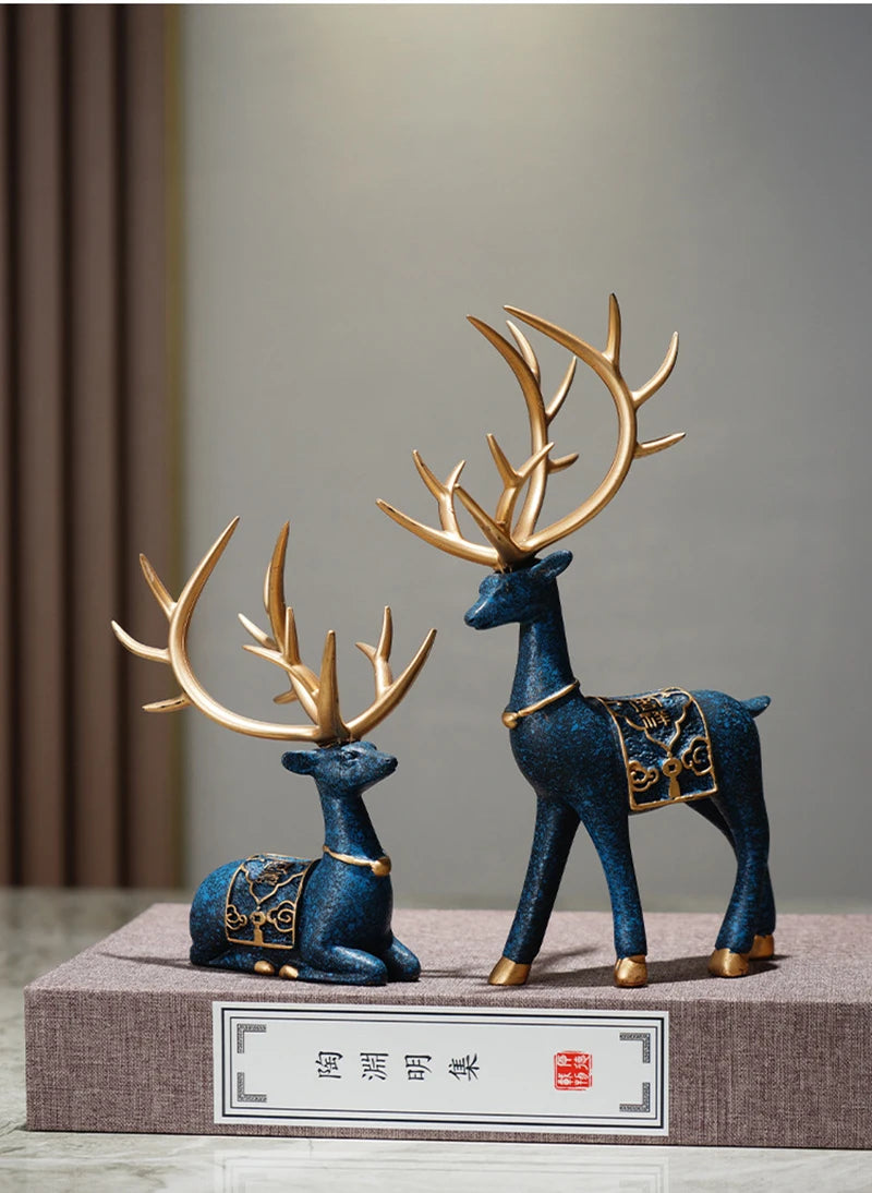 A set of two resin deer figurines in blue and gold, used for Christmas or home decor.