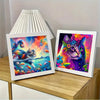 A framed piece of colorful cartoon cross stitch art featuring a cat surrounded by vibrant flowers and foliage.