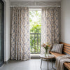 Light blue floral curtains hanging in a window frame with a wooden bench and glass table.