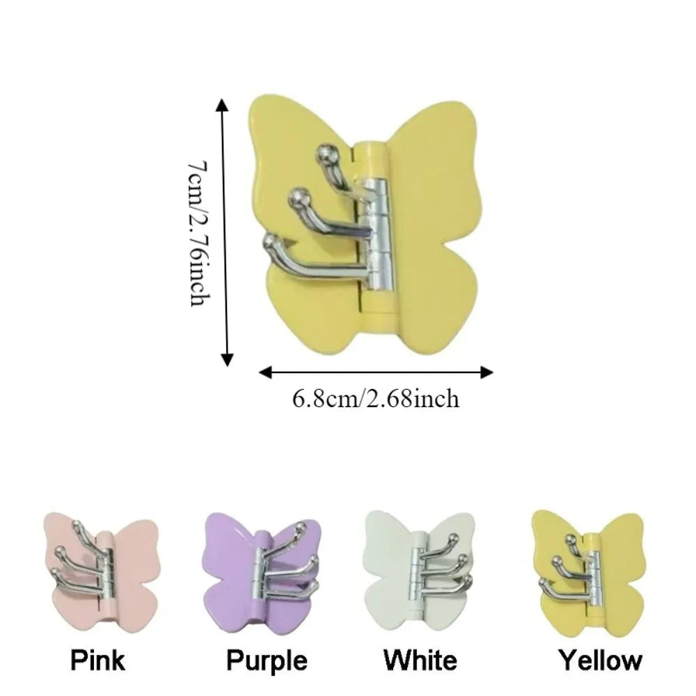 Un juego de cuatro ganchos decorativos para la pared con mariposas giratorias en rosa, púrpura, blanco y amarillo.
