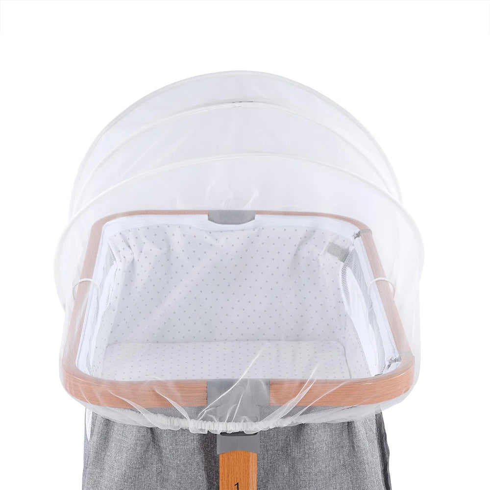A clear mosquito net cover for a baby's bassinet or crib, shown resting on a wooden frame.