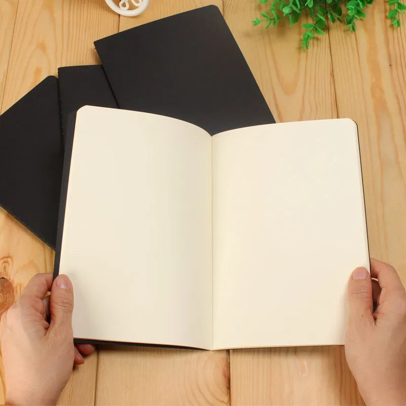 A blank A6 Kraft paper notebook open to show the interior pages on a wooden surface.