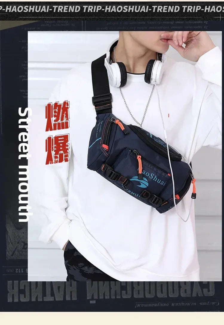 A person wearing a white sweatshirt holds a dark blue tactical chest bag with an orange strap and silver chain.