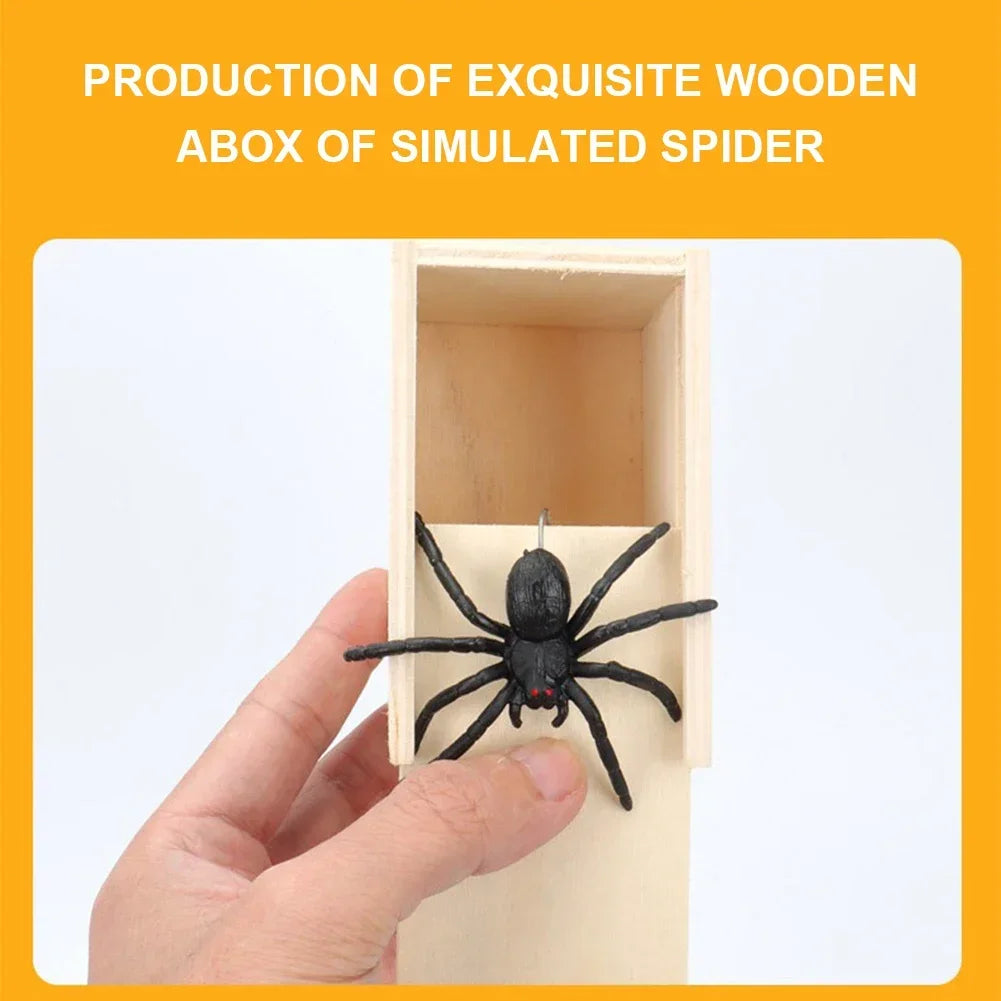 A hand is holding a black spider toy inside a wooden box designed to simulate a spider.
