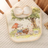 A soft cotton baby bib featuring a cute illustration of a panda and mushrooms on a light background.