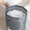 A gray drawstring laundry bag filled with white clothes, shown in a close-up view.