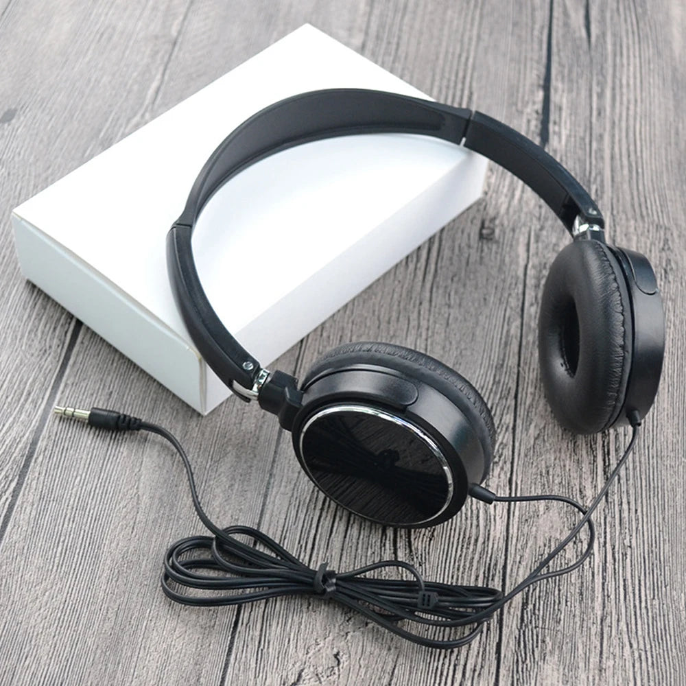 Black foldable stereo wired headphones with a 3.5mm jack resting on a white box.