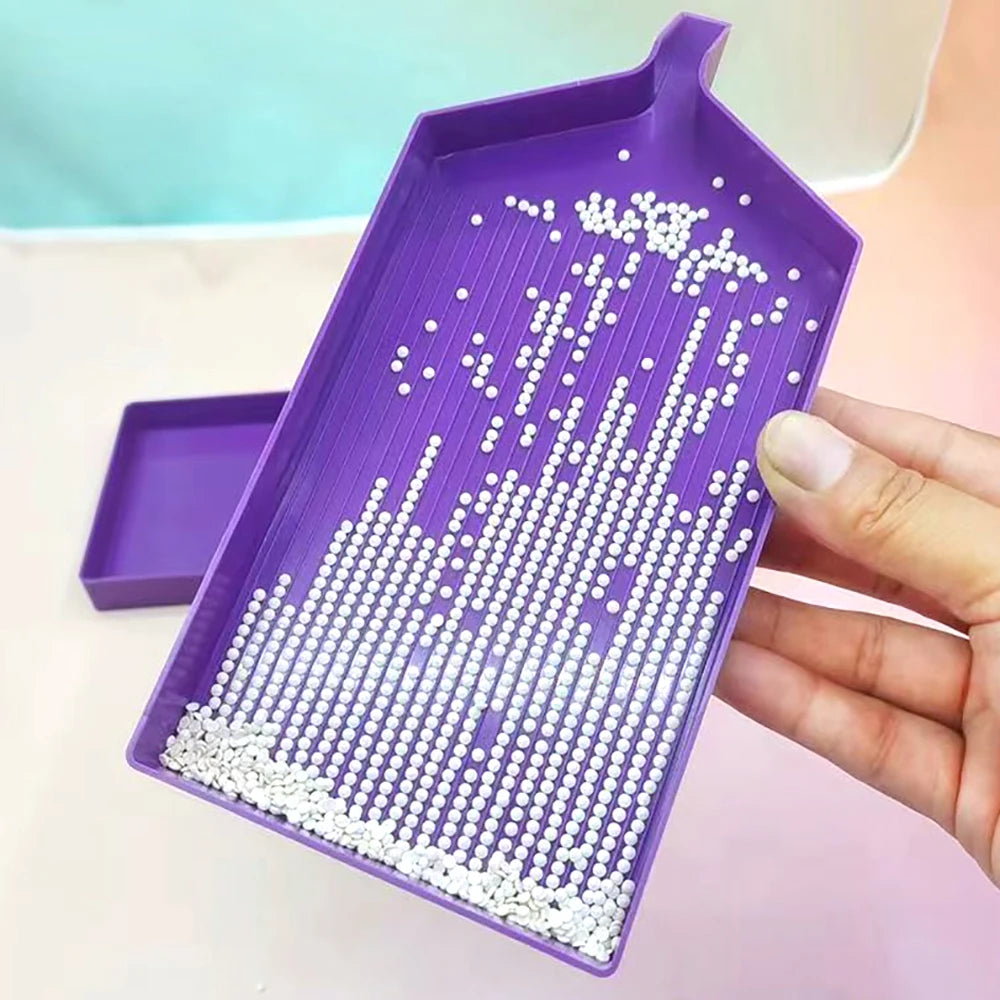 A purple diamond painting organizer tray filled with white seed beads and organized plastic storage case.
