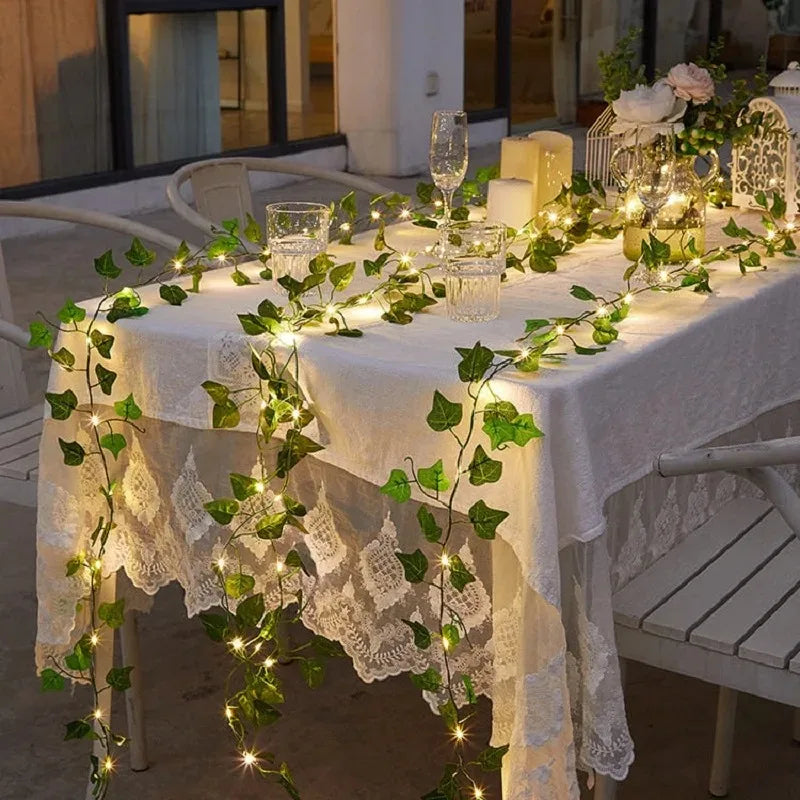 Table blanche décorée d'une guirlande de lierre vert avec des lumières LED solaires et de la dentelle.