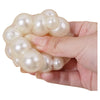Eine Hand hält eine Ansammlung weißer Perlen, die als quichelbare Stressball dient.