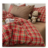 A vintage red plaid duvet cover set featuring a checkered pattern and a teddy bear pillow on a bed.