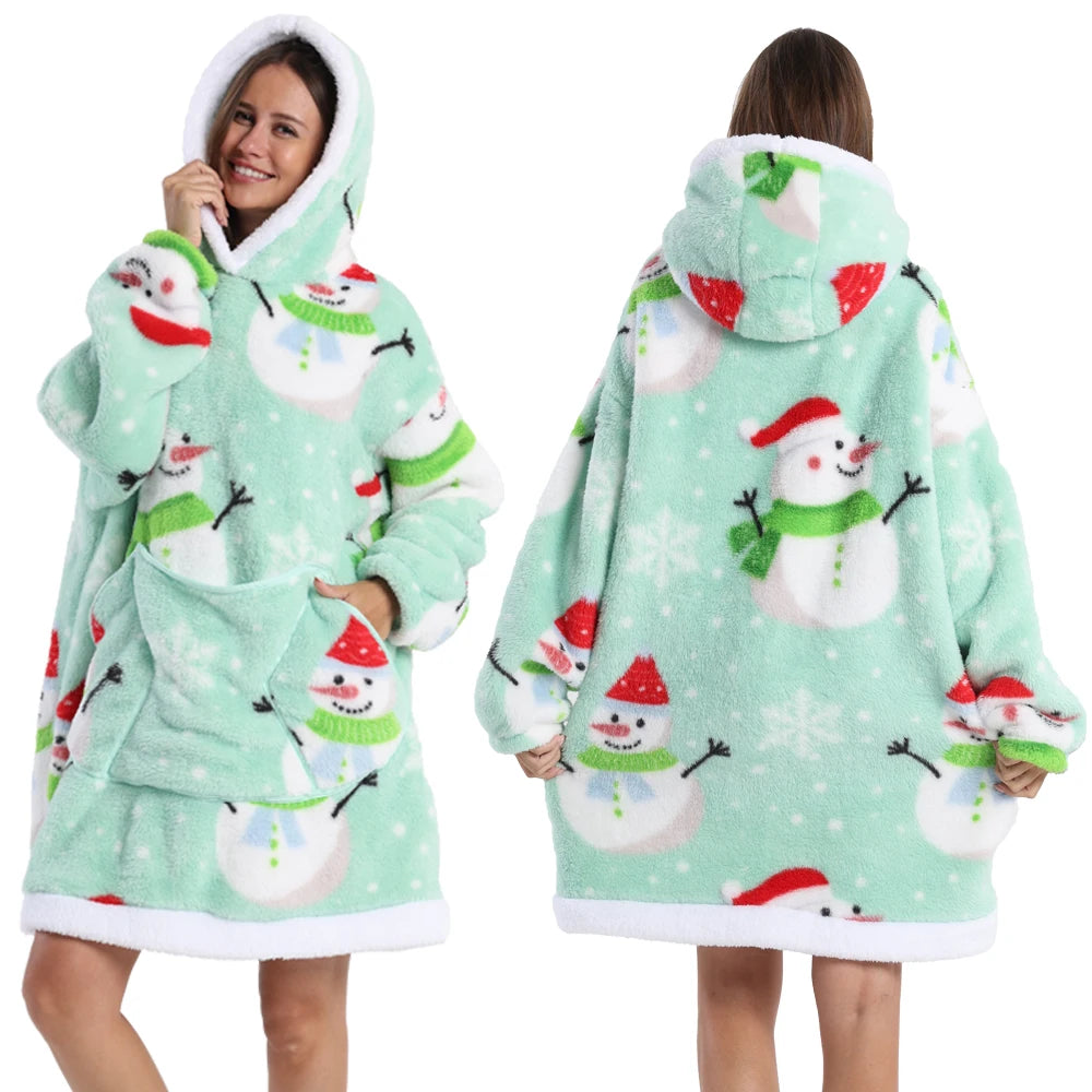 Eine Frau modelliert einen hellgrünen, patchworkartigen, oversized Fleece-Hoodie mit weißen und roten Schneeflocken-Designs.
