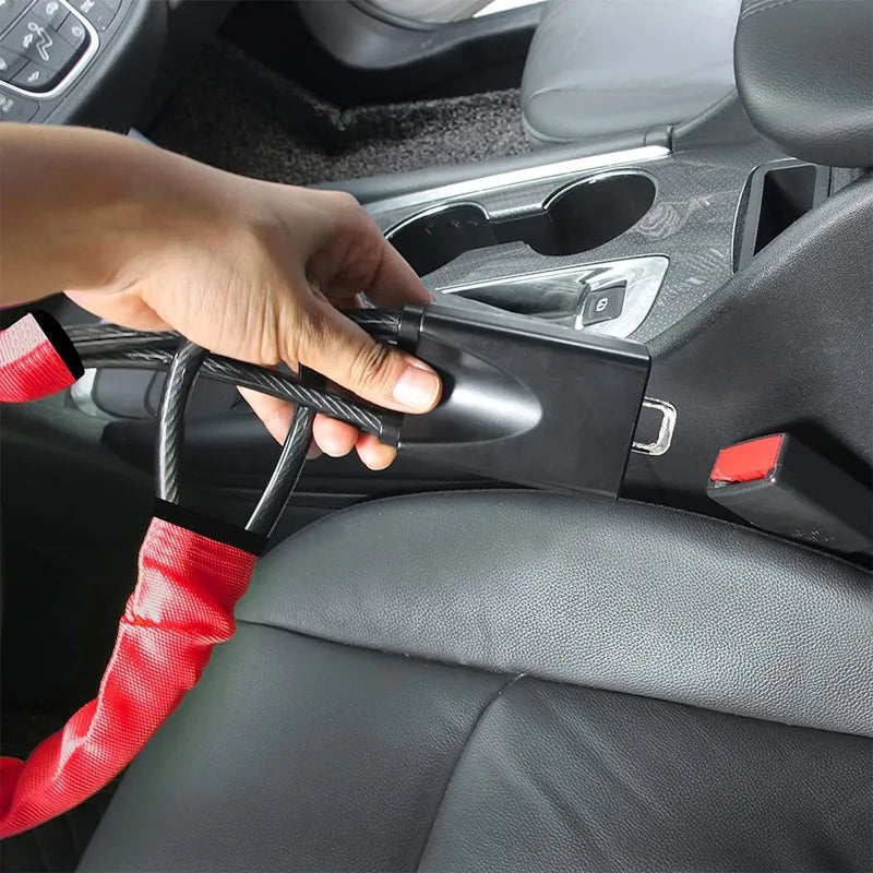 Une main utilise un loquet de volant universel noir avec un ancrage de ceinture rouge dans l'intérieur d'une voiture.