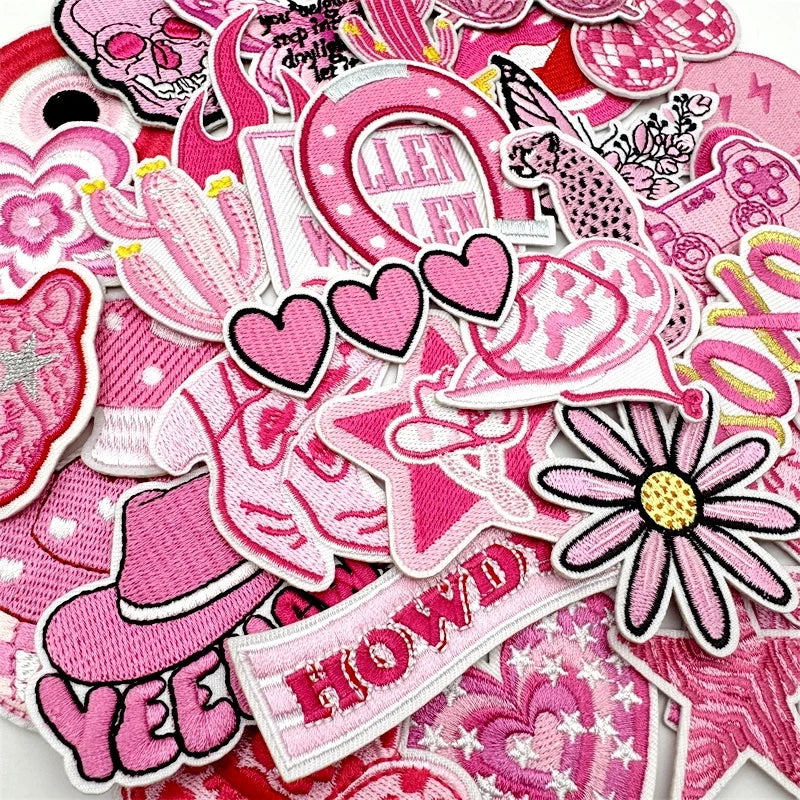 Assorted pink embroidered iron-on patches featuring various designs like hearts flowers and text for DIY clothing