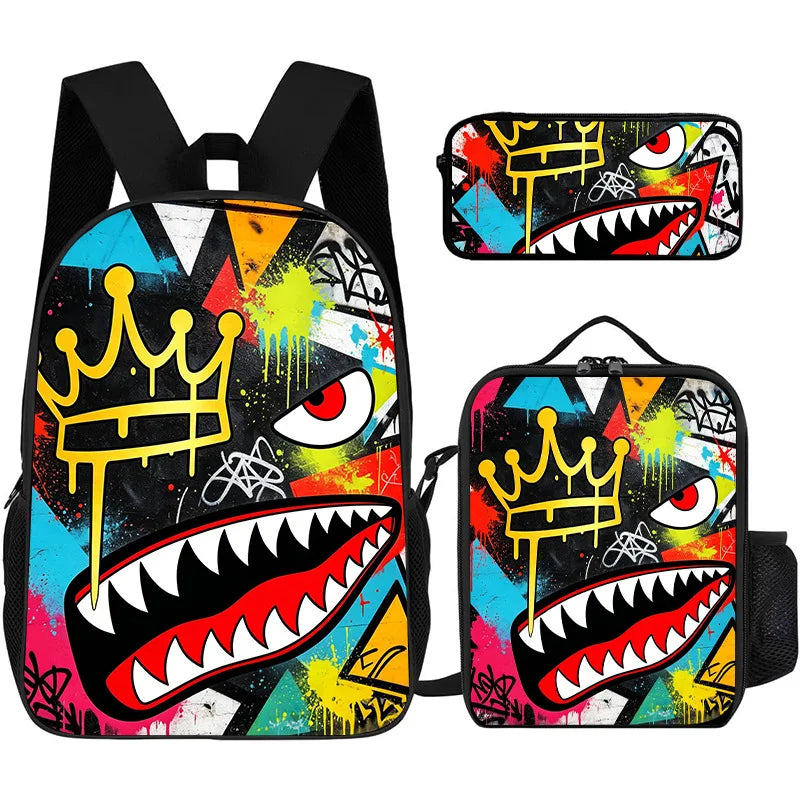 A set of three graphic cartoon print backpacks featuring a stylized shark head and crown design in vibrant colors.