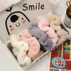 A collection of soft, fluffy coil hair ties in pastel shades including pink, lavender, and beige, displayed in a white box.