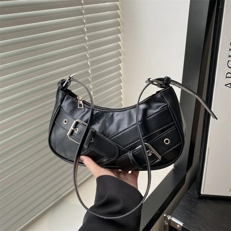 A black Y2K vintage PU leather crossbody bag being held by a hand next to a window blind.