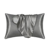 Una funda de almohada de satén de seda gris suave, mostrada doblada y drapeada.