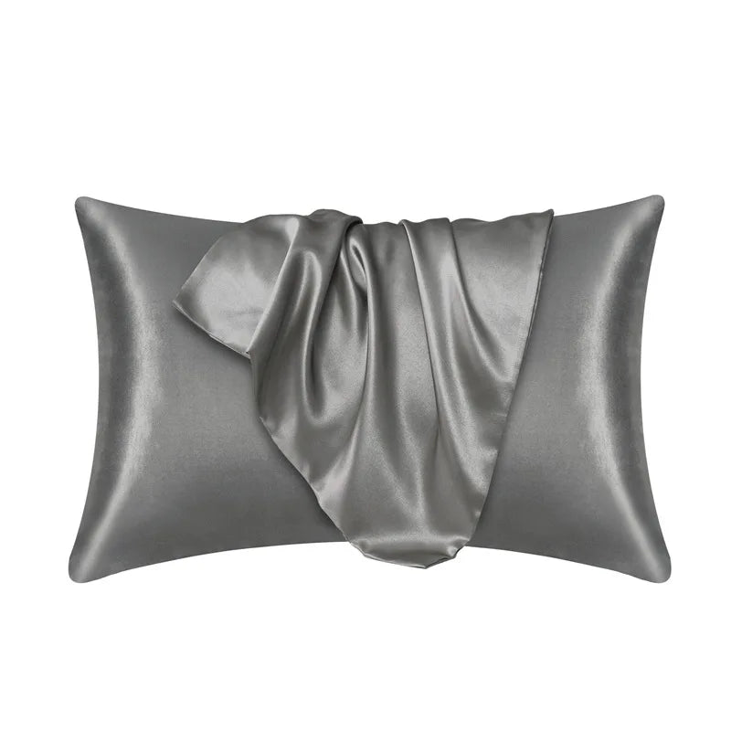 Una funda de almohada de satén de seda gris suave, mostrada doblada y drapeada.