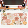 A pink and orange floral mouse pad with a non-slip surface is displayed on a wooden desk.