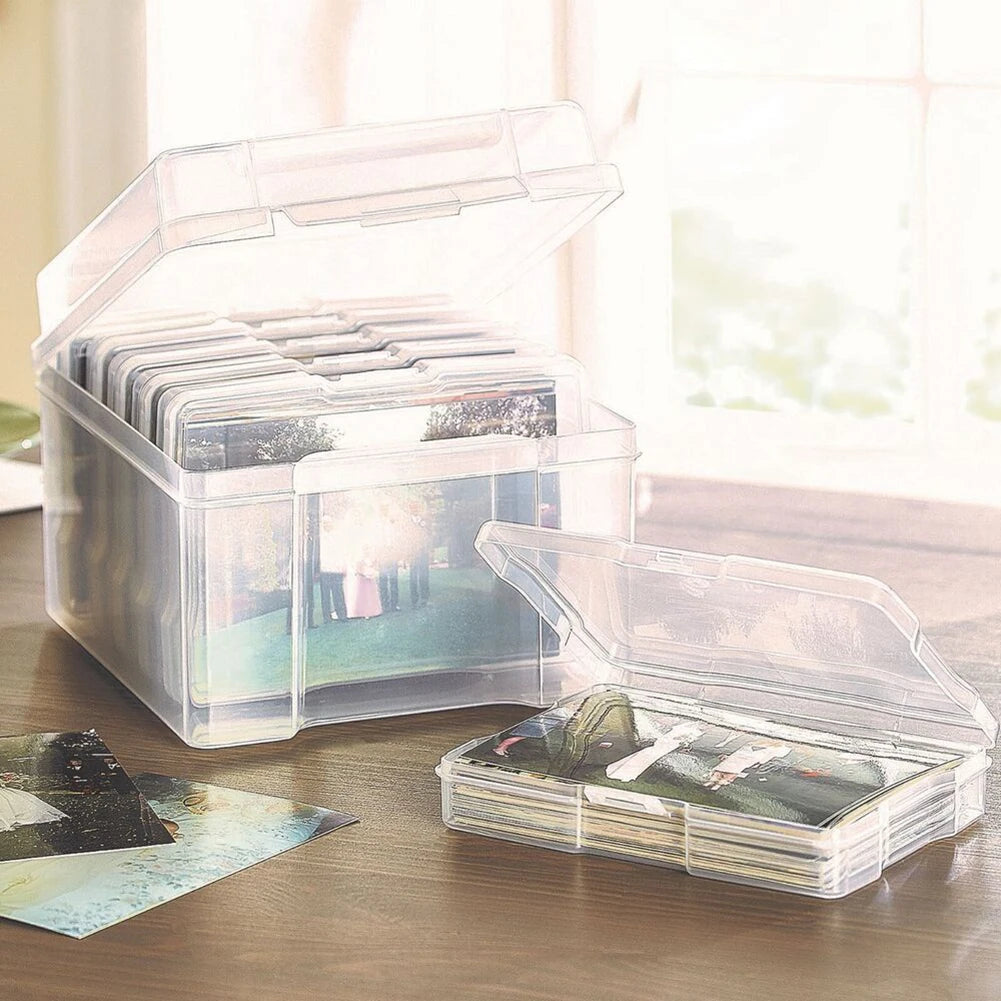 Clear photo storage boxes with lids and stacks of 4x6 pictures on a wooden surface