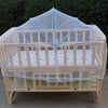 A wooden baby crib covered with a sheer, breathable mosquito net for protection.