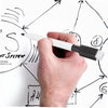 A hand holds a white dry erase marker with a black tip, demonstrating its use on a whiteboard with drawn diagrams.