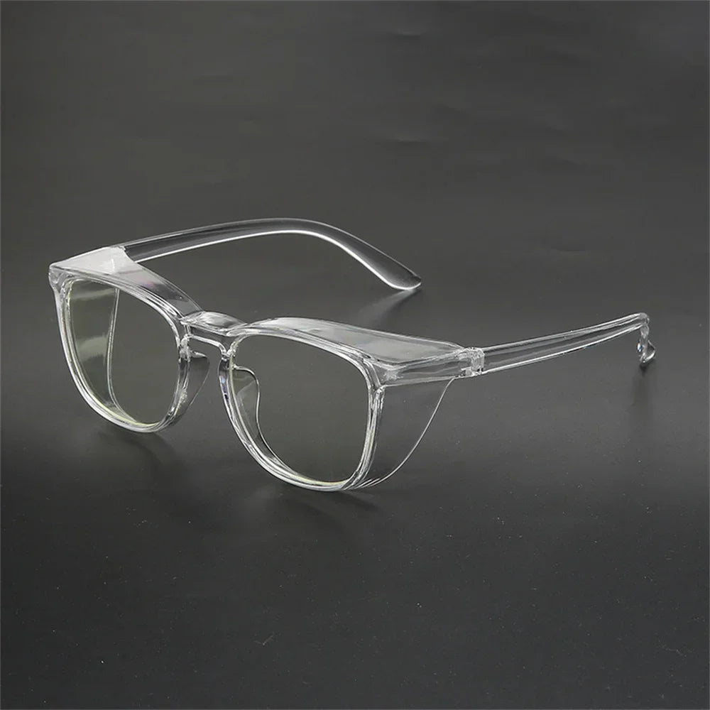Lunettes de sécurité en plastique transparent anti-lumière bleue et coupe-vent posées sur une surface sombre.