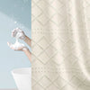 A beige boho waterproof shower curtain with diamond pattern and tassels hanging in a bathroom.