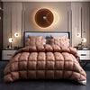 A luxurious brown quilted duvet and pillows displayed on a bed with modern gold accents.